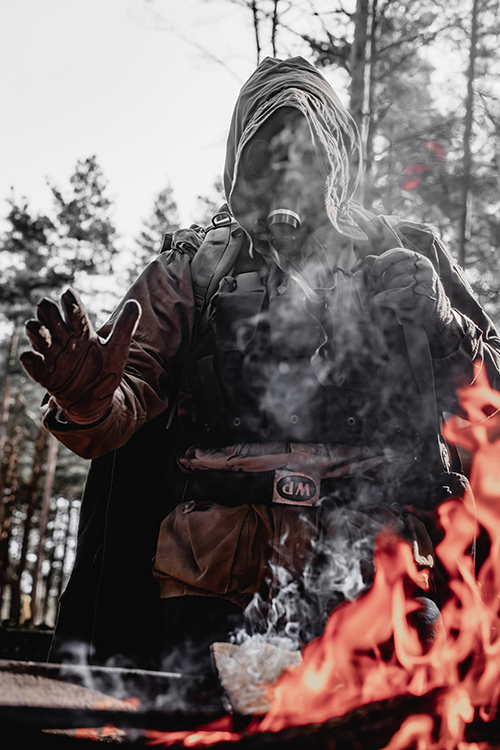 Stalker warming hands by a fire in the wasteland